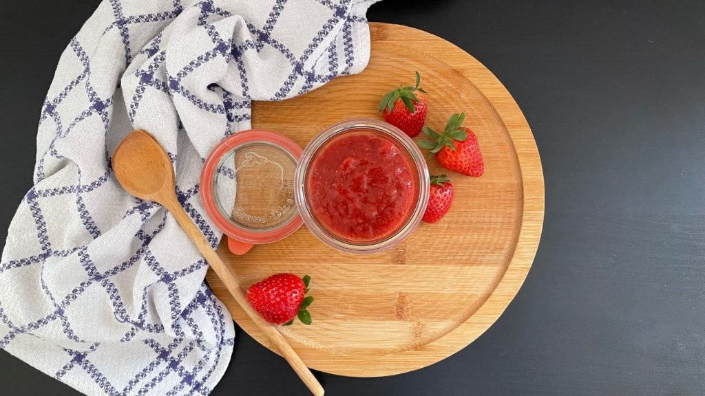 Rhabarber-Erdbeer-Marmelade mit Kochlöffel und Geschirrtuch